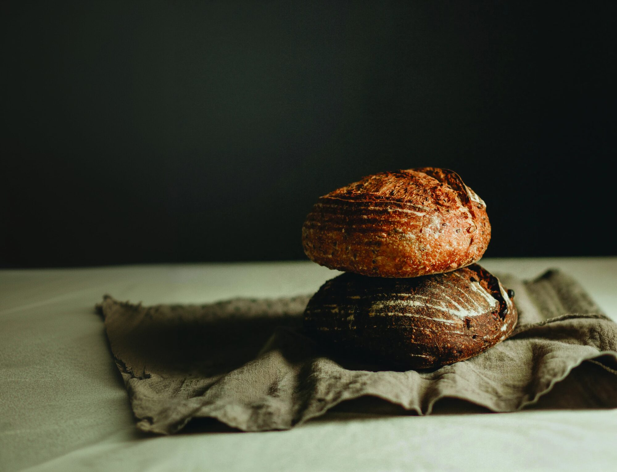 Due pagnotte di pane artigianale appena sfornate, appoggiate su un telo di lino